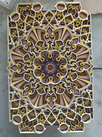 An ornate rectangular decorative panel or tray featuring a highly detailed symmetrical mandala and floral cutout design in gold, purple, brown, and white, photographed from directly above on a gray surface. image 4