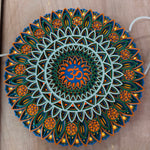 A circular LED mandala night light with a 3D layered design, featuring a central blue Om symbol surrounded by intricate floral patterns in orange, teal, and white, shown lit on a wooden surface. image 6