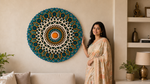 A woman in a beige and peach saree stands next to a large, circular, mandala-style wall hanging with intricate teal, white, and orange patterns on a beige wall in a styled living room. image 12